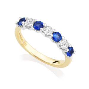 An 18ct yellow gold and platinum sapphire and diamond seven stone half eternity ring, belonging to H. L. Brown's Volante collection.