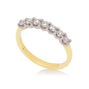 An 18ct yellow gold and platinum round brilliant cut diamond seven stone half eternity ring, belonging to H. L. Brown's Volante collection.