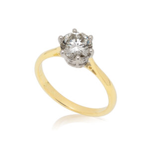An 18ct yellow and white gold round brilliant cut diamond set solitaire ring with a cornet setting.