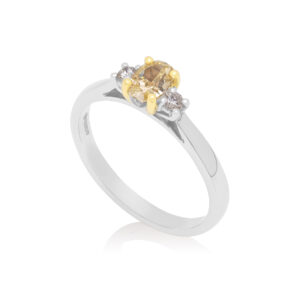 Platinum oval yellow diamond and brilliant cut diamond three stone ring with an 18ct yellow gold claw setting.