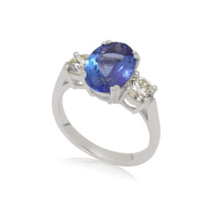 A platinum oval shaped tanzanite and round brilliant cut diamond three stone ring.