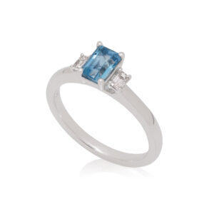 A platinum emerald cut aquamarine and diamond set three stone ring.
