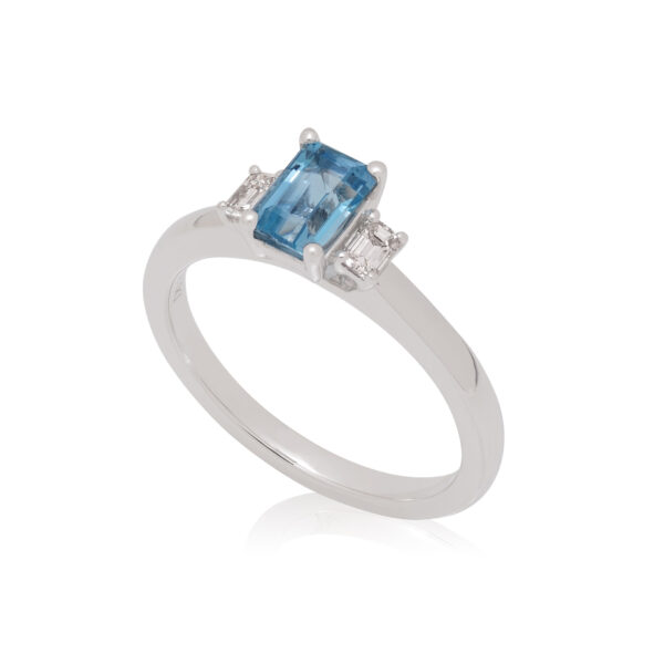 A platinum emerald cut aquamarine and diamond set three stone ring.