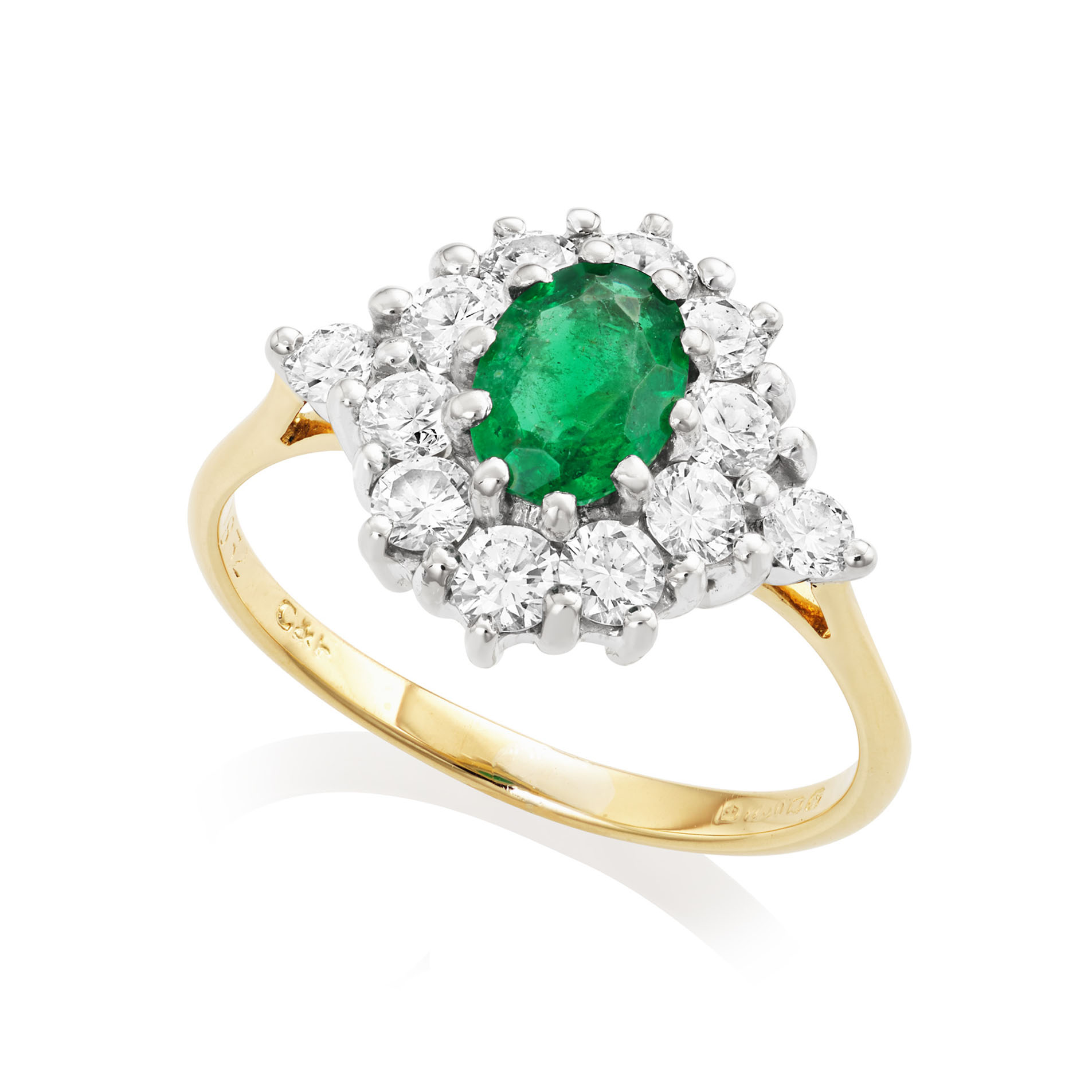 An 18ct yellow and white gold oval shaped emerald and brilliant cut diamond cluster ring. Hallmarked London 1987.