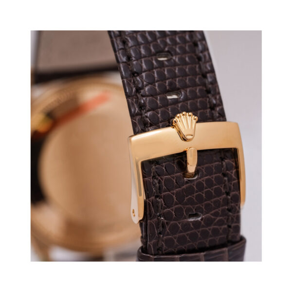 A vintage Rolex, Oyster Perpetual with a 34mm 18ct yellow gold case with a brown lizard strap with an 18ct yellow gold buckle, featuring a fluted bezel and a textured champagne coloured dial.