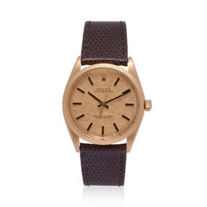 A vintage Rolex, Oyster Perpetual with a 34mm 18ct yellow gold case with a brown lizard strap with an 18ct yellow gold buckle, featuring a fluted bezel and a textured champagne coloured dial.