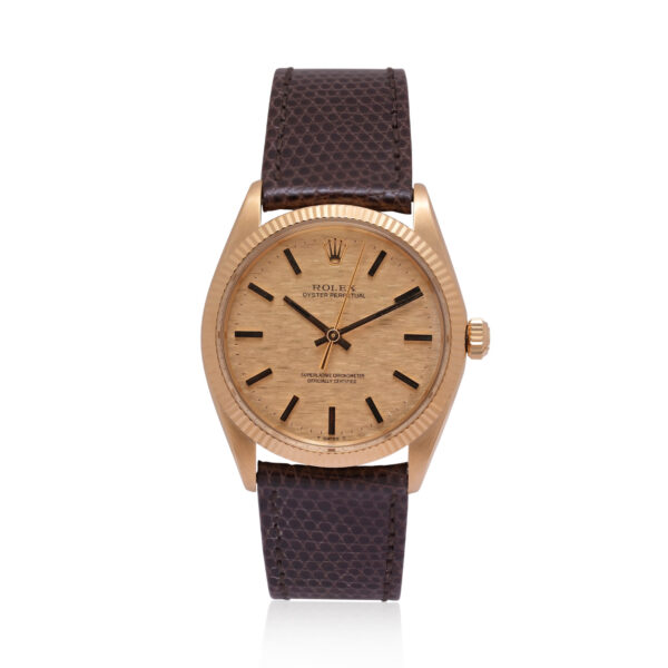 A vintage Rolex, Oyster Perpetual with a 34mm 18ct yellow gold case with a brown lizard strap with an 18ct yellow gold buckle, featuring a fluted bezel and a textured champagne coloured dial.