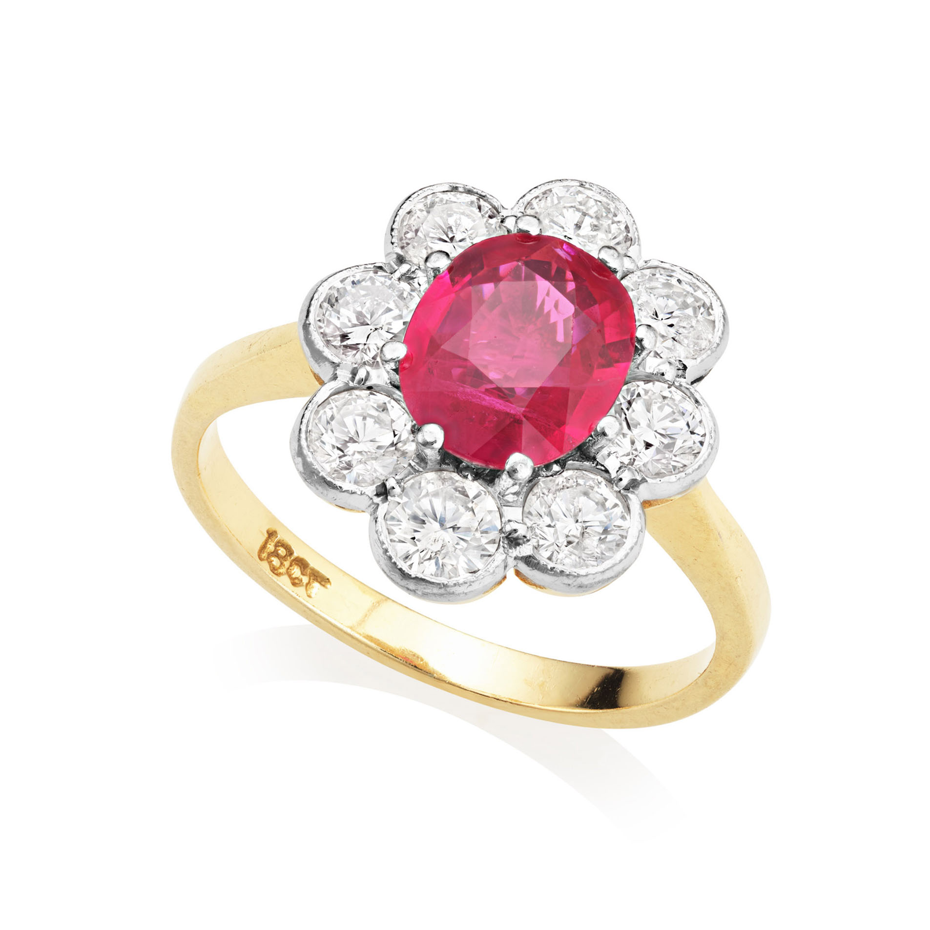 An 18ct yellow and white gold ruby and diamond cluster ring. The claw set oval ruby is surrounded by eight millegrain set round brilliant cut diamonds.