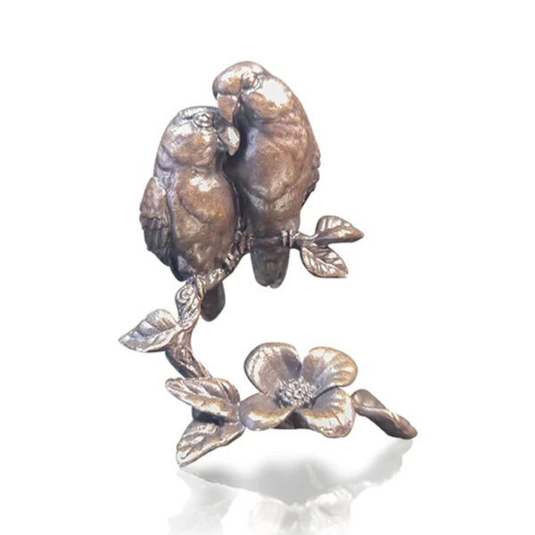Made from solid foundry bronze, this piece depicts two birds sitting on a branch leaning in towards each other.