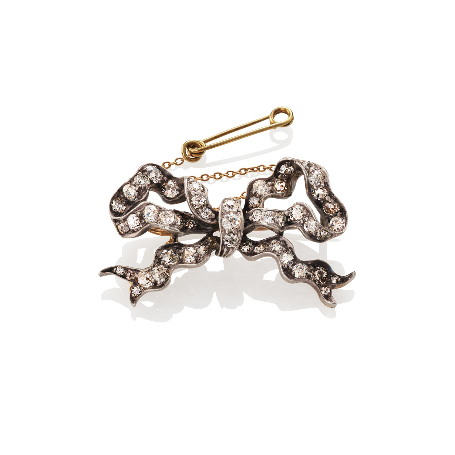 An Edwardian old brilliant cut and swiss cut diamond set bow brooch with a pendant hook, featuring a safety chain.