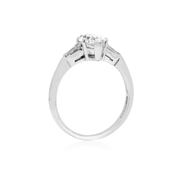 An 18ct white gold marquite and brilliant cut diamond solitaire ring with tapered baguette cut diamond shoulders.