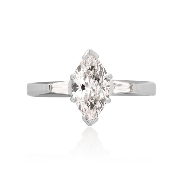 An 18ct white gold marquite and brilliant cut diamond solitaire ring with tapered baguette cut diamond shoulders.