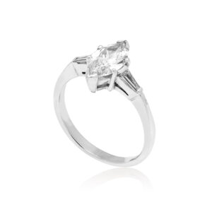 An 18ct white gold marquite and brilliant cut diamond solitaire ring with tapered baguette cut diamond shoulders.