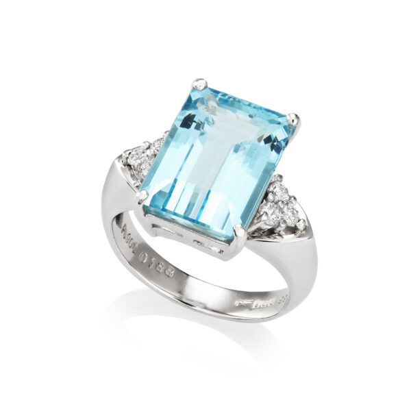 An American aquamarine ring set with three trefoil style diamonds to each shoulder.
