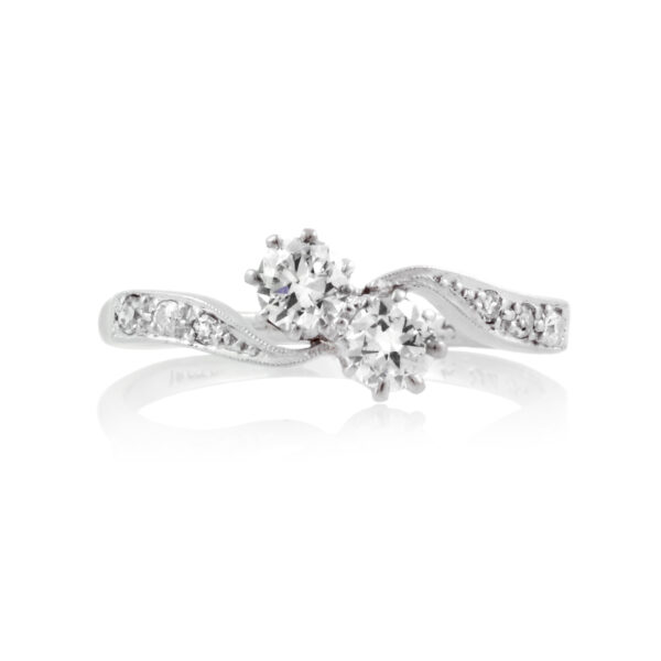 A two stone diamond crossover ring with diamond set shoulders, featuring eight diamonds in total.