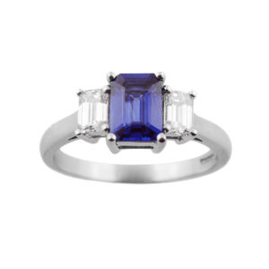 An 18ct white gold emerald cut sapphire and diamond three stone ring.