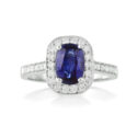 An 18ct white gold, oval shaped sapphire and diamond set cluster ring with diamond set shoulders.