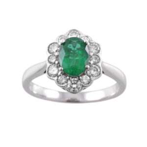 An 18ct white gold oval emerald and round brilliant cut diamond cluster ring with millegrain setting to the edges.
