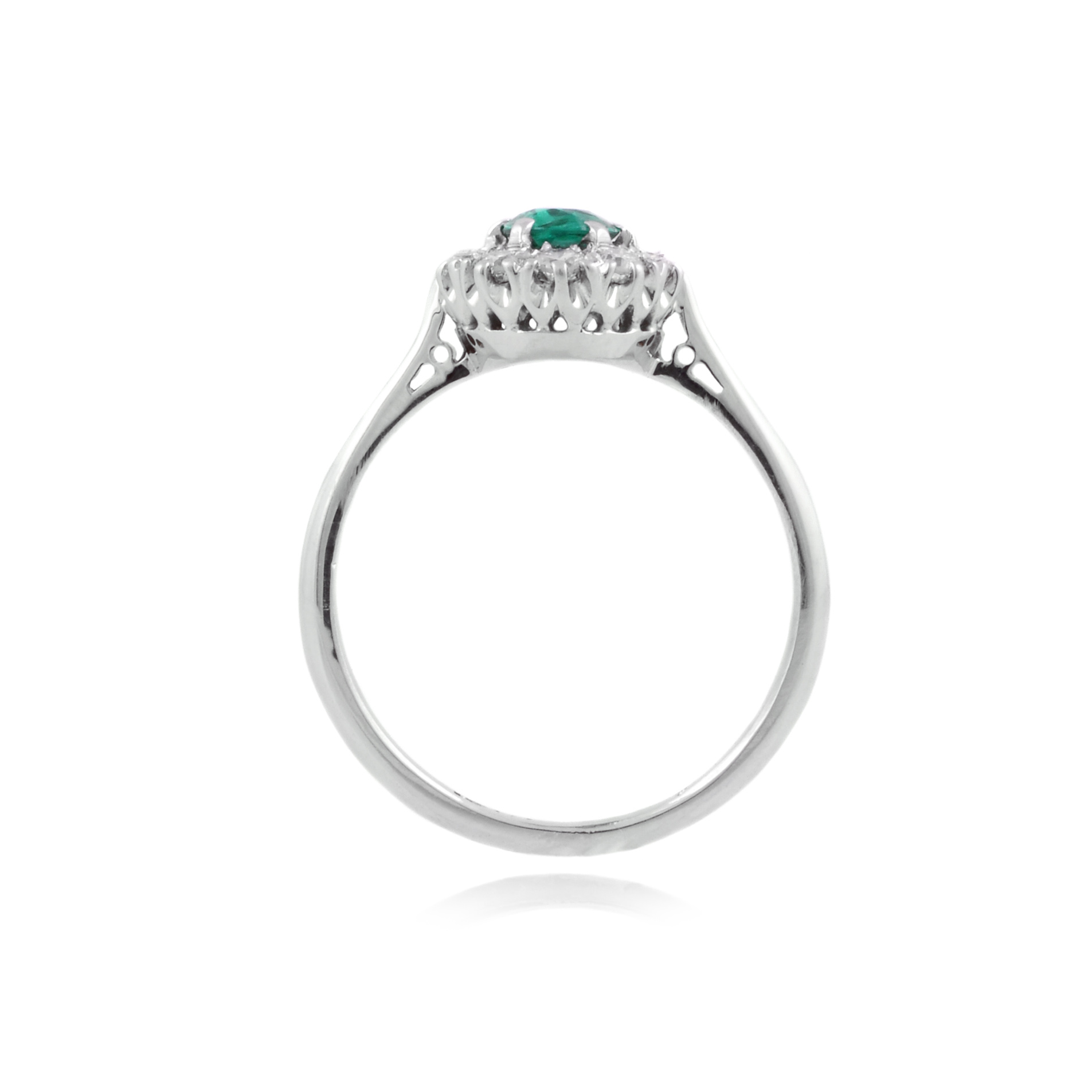 An 18ct white gold, oval shaped emerald and diamond set eleven stone cluster ring.