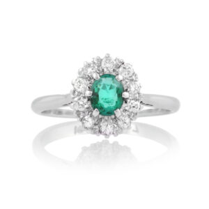 An 18ct white gold, oval shaped emerald and diamond set eleven stone cluster ring.