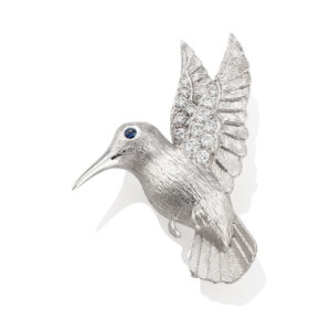 An 18ct white gold brooch modelled as a kingfisher in flight with diamond set wings and a sapphire set eye.