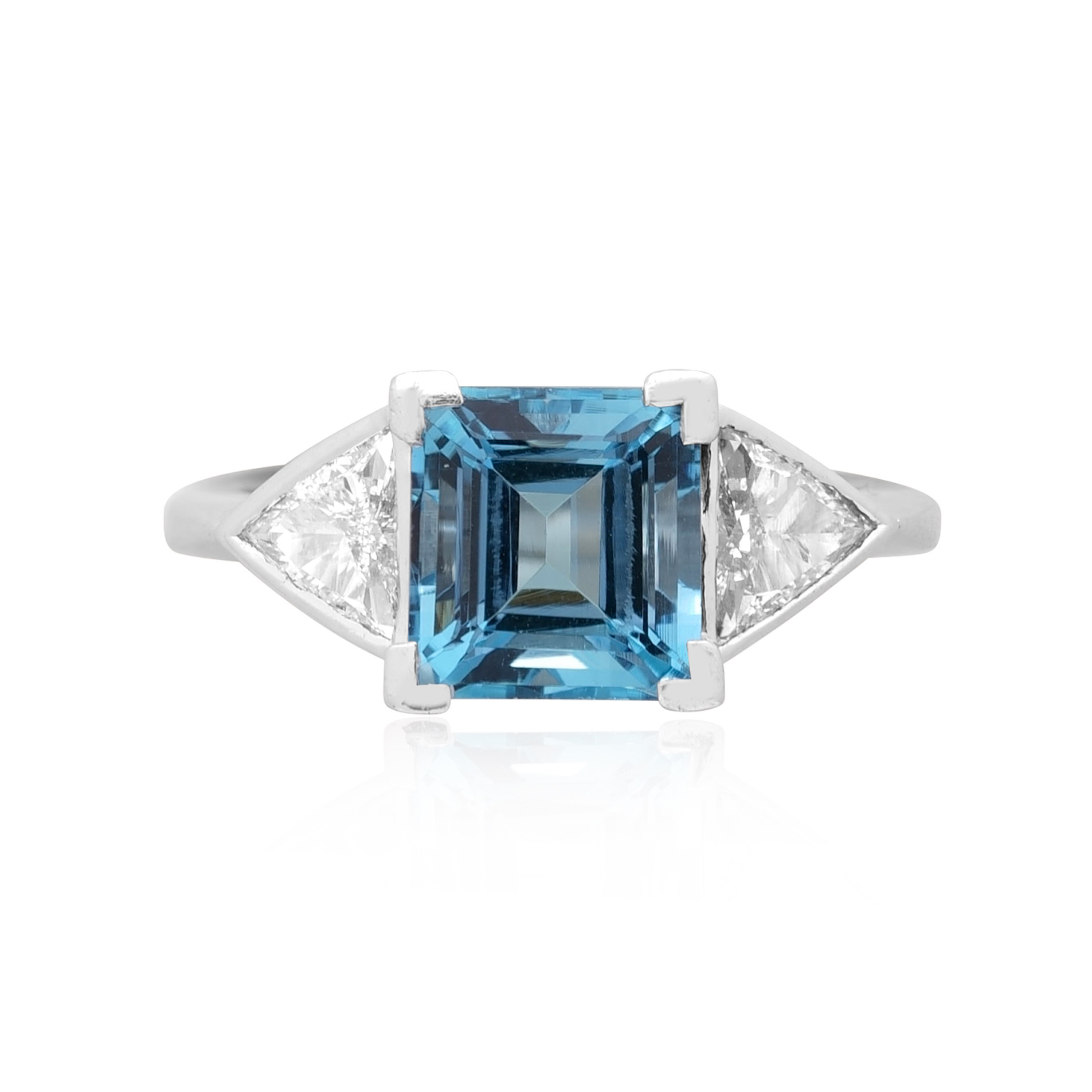 18ct White Gold Aquamarine & Diamond Three Stone Ring An 18ct white gold square cut aquamarine and brilliant cut diamond three stone ring, with brilliant cut diamonds set to the shoulders.