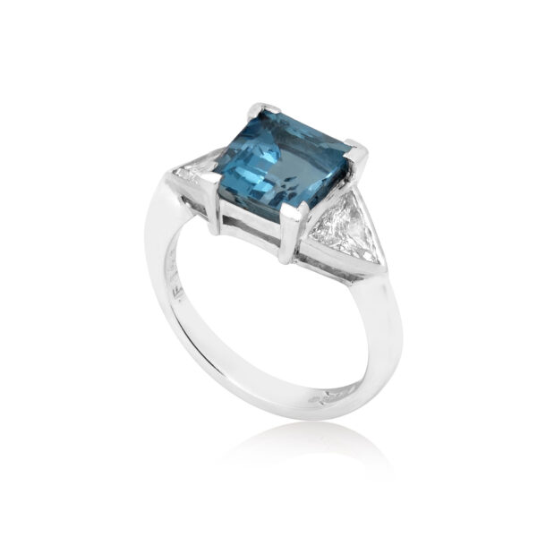 An 18ct white gold square cut aquamarine and brilliant cut diamond three stone ring, with brilliant cut diamonds set to the shoulders.