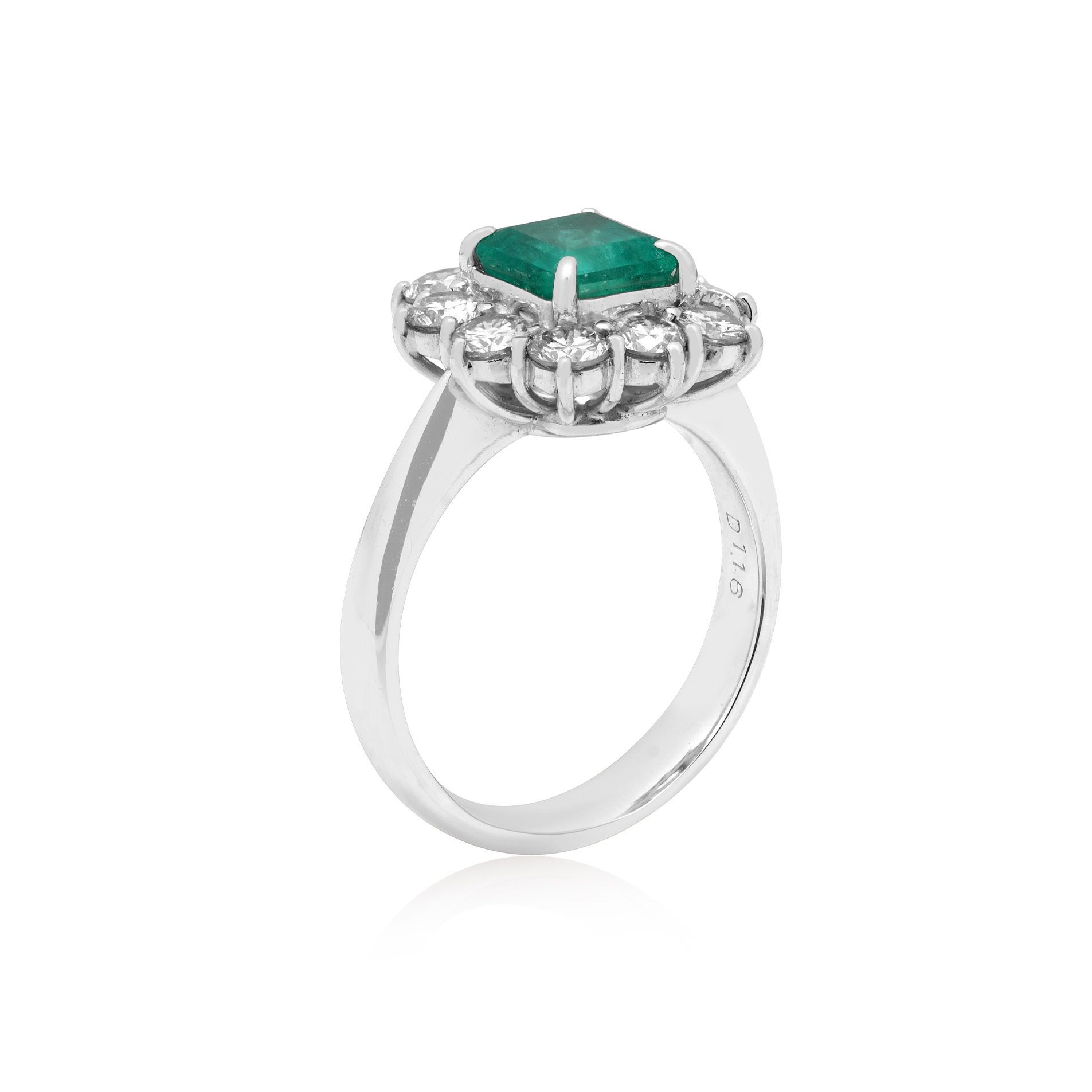 Platinum Emerald Cut Emerald & Diamond Cluster Ring A platinum emerald cut emerald cluster ring surrounded by ten round brilliant cut diamonds.