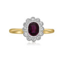 An Edwardian 18ct yellow gold and platinum oval shaped ruby and diamond cluster ring. The oval milllegrain ruby is surrounded by twelve similarly set eight cut diamonds.