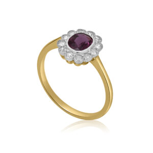 An Edwardian 18ct yellow gold and platinum oval shaped ruby and diamond cluster ring. The oval milllegrain ruby is surrounded by twelve similarly set eight cut diamonds.