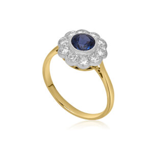 A mid 20th century sapphire and diamond flower cluster ring. The round faceted millegrain set sapphire is surrounded by ten old brilliant cut diamonds.