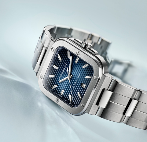 A stainless steel Herbelin Cap Camarat watch with a blue dial on a light blue background.