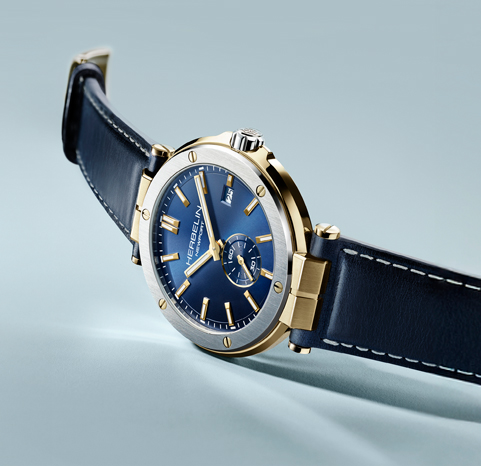 A Herbelin Newport watch with a blue dial and blue strap on a light blue background.
