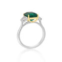 A platinum green emerald and trapeze cut diamond three stone ring.