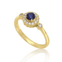 An 18ct yellow gold round sapphire and diamond millgrain set cluster ring with two diamonds set on each shoulder.