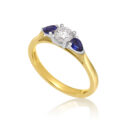 An 18ct yellow and white gold pear shaped sapphire and round brilliant cut diamond three stone ring.