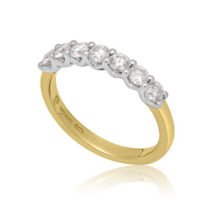 An 18ct yellow gold and platinum seven stone diamond half eternity ring with a v-collet setting, belonging to the H. L. Brown Volante Collection.
