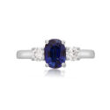 A platinum oval sapphire and round brilliant cut diamond three stone ring.