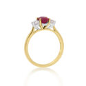 An 18ct yellow gold oval ruby and round brilliant cut diamond three stone ring.