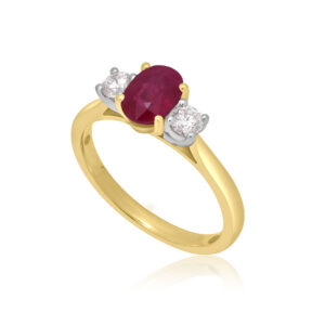 An 18ct yellow gold oval ruby and round brilliant cut diamond three stone ring.