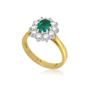 An 18ct yellow and white gold oval emerald and diamond cluster ring.
