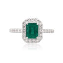 An 18ct white gold emerald and brilliant cut diamond cluster ring with diamond set shoulders.
