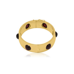 An 18ct yellow gold, hinged bangle set with six evenly spaced round cabochon cut red garnets, with French control marks featured on the tongue.