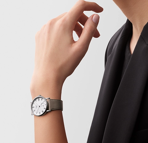 A woman wearing a Longines watch with a white dial.