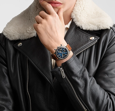 A man wearing a Longines watch with a blue dial and a brown strap.