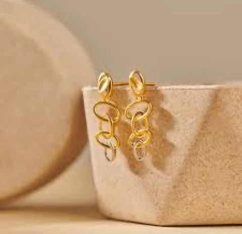 A pair of yellow gold earrings on a ceramic block.