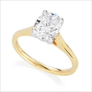 A yellow gold and platinum mounted oval-shaped diamond solitaire ring on a white background.