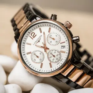 A two-tone Longines watch with a chronograph and a white dial.