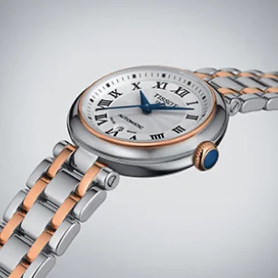 A two tone Tissot watch with a silver dial on a grey background.